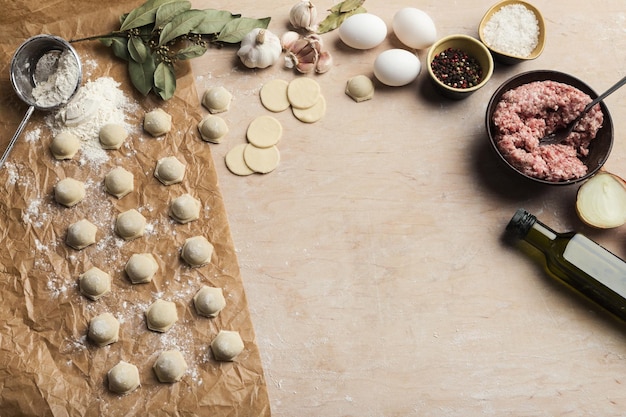 Processo de fazer bolinhos de massa com carne na mesa de madeira coberta com farinha. Alimentos e ingredientes tradicionais caseiros.