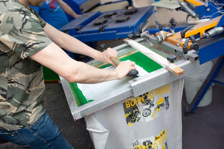 Processo de impressão da serigrafia na fábrica de roupas. Tintas coloridas para moldura, rodo e plastisol