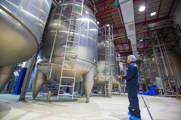 Processo de inspeção de trabalho masculino - adega de leite em pó na fábrica com tanques verticais de aço inoxidável