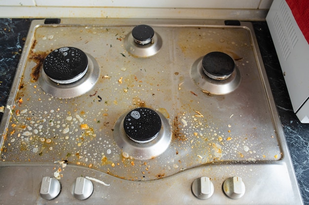 Processo de lavagem do fogão a gás. Close-up do fogão a gás sujo coberto com líquido de lavagem química. Conceito de tarefas domésticas ou tarefas domésticas.