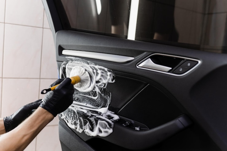 Foto processo de limpeza de espuma e detergente com escova dentro da maçaneta da porta do carro serviço de detalhamento do carro trabalhador no serviço de limpeza lavando o interior do couro do automóvel dos clientes