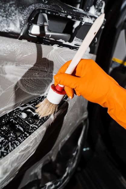 Processo de limpeza de espuma e detergente com escova painel de cartão de porta de carro Serviço de detalhamento de carro Trabalhador em serviço de limpeza lavando interior de automóveis de clientes