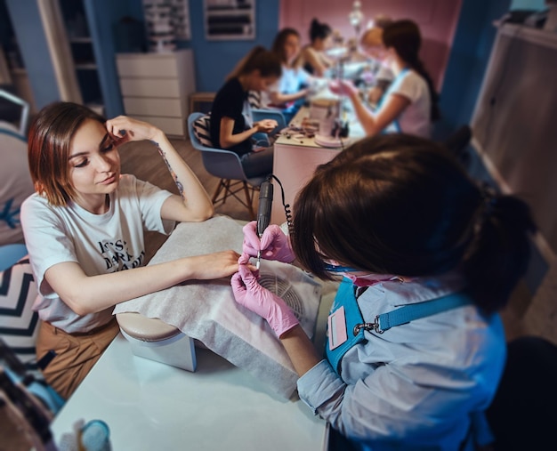 Processo de manicure no salão de beleza com duas mulheres atraentes e felizes.