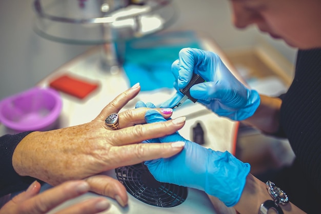 Processo de manicure no salão de beleza perto das mãos femininas