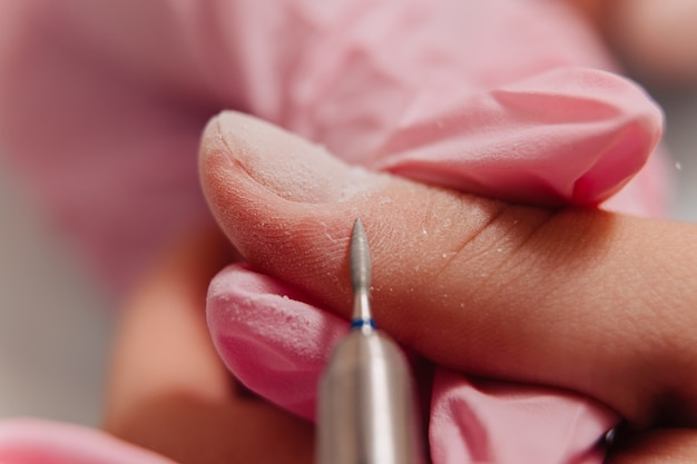 Processo de manicure. O mestre lustra a unha usando uma máquina automatizada. Removedor de polimento de broca.