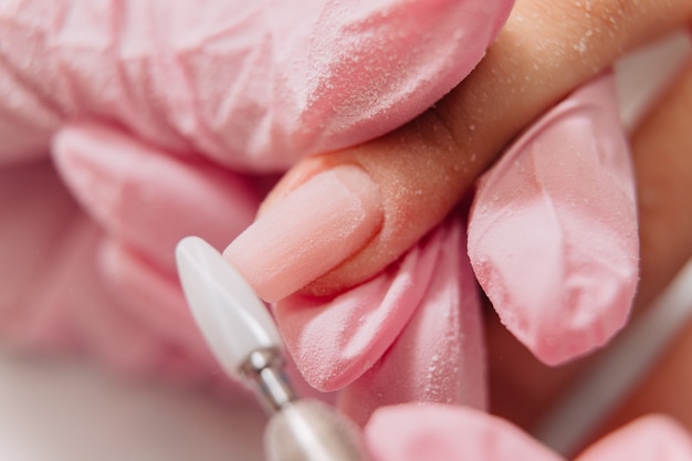 Processo de manicure. O mestre lustra a unha usando uma máquina automatizada. Removedor de polimento de broca.