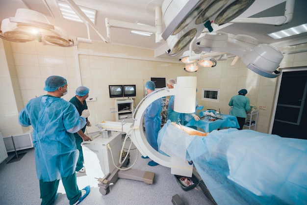 Processo de operação da cirurgia de trauma. Grupo de cirurgiões na sala de cirurgia com equipamento de raio-x de cirurgia.
