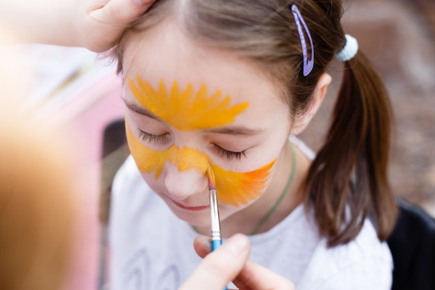 Processo de pintura infantil no rosto da menina