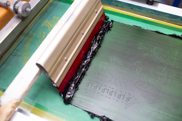 Processo de serigrafia em silk screen em rodo de moldura de fábrica de roupas e tintas coloridas de plastisol