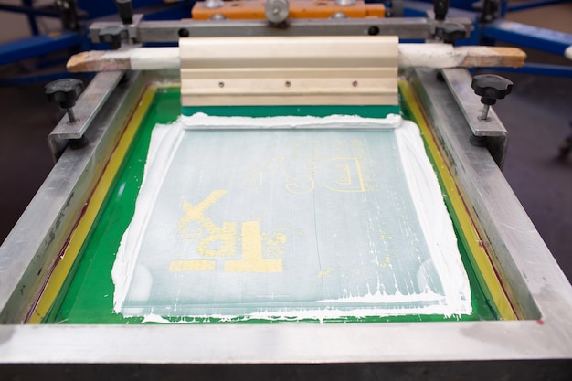 Foto processo de serigrafia em silk screen em rodo de moldura de fábrica de roupas e tintas coloridas de plastisol