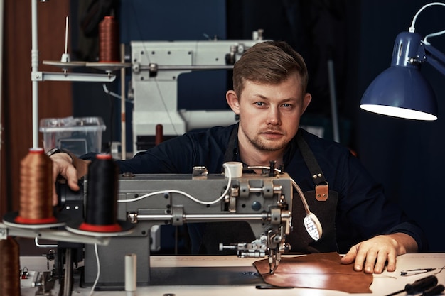 Processo de trabalho do artesão de couro. Curtidor ou skinner costura couro em uma máquina de costura especial, close up.worker costurando na máquina de costura.