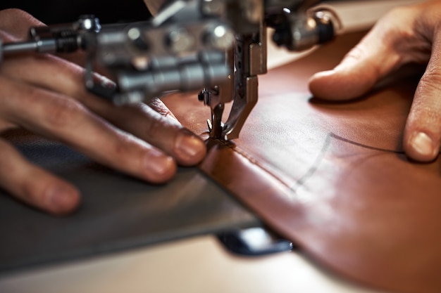 Processo de trabalho do artesão de couro. Curtidor ou skinner costura couro em uma máquina de costura especial, close up.worker costurando na máquina de costura.