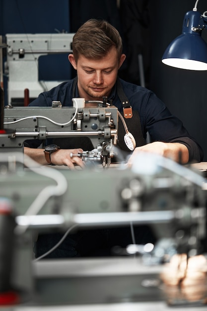 Processo de trabalho do artesão de couro. curtidor ou skinner costura couro em uma máquina de costura especial, close up.worker costurando na máquina de costura.