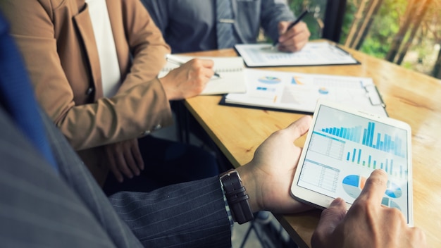 Processo de trabalho em equipe. Equipe de jovens gerentes de negócios trabalhando com um novo projeto de inicialização. Laboratório na mesa de madeira, teclado de digitação, mensagem de texto, analise planos de gráficos