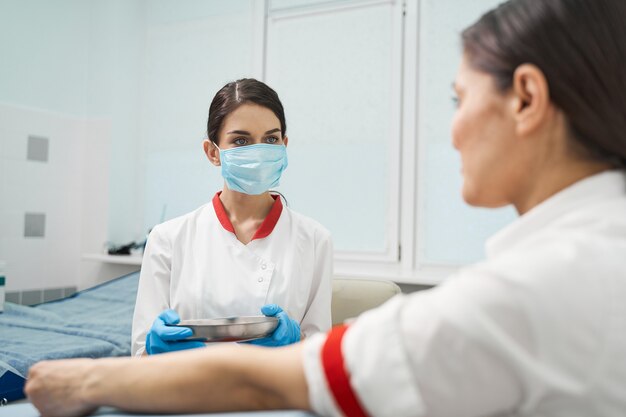 Processo de trabalho. trabalhador médico atento olhando para seu paciente enquanto coleta sangue para o teste