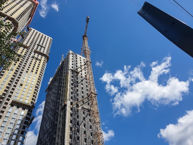 Processo moderno de construção de arranha-céus ou edifícios altos no fundo do céu azul Vista em perspectiva de baixo Fundo urbano industrial Arquitetura moderna