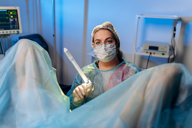 Foto proctologista cirurgiã profissional realizando operação usando dispositivos especiais para colonoscopia na sala de cirurgia no hospital conceito cirúrgico urgente