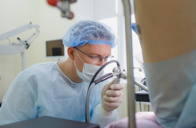 Foto un proctólogo examina a un paciente de colonoscopia rectal acostado en una silla médica en el consultorio quirúrgico