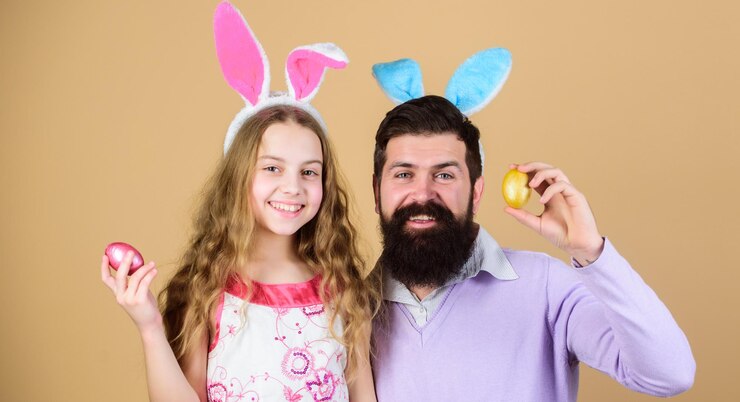 Foto procurando por ovo família de pai e filha sorrindo em orelhas de coelhinho da páscoa família feliz família comemorando a páscoa feliz pai e filho com ovos de páscoa coloridos família na caça anual aos ovos de páscoa