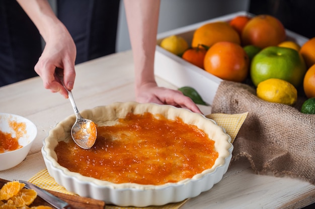 Produção de bolo com marmelada cítrica e fatias de tangerina