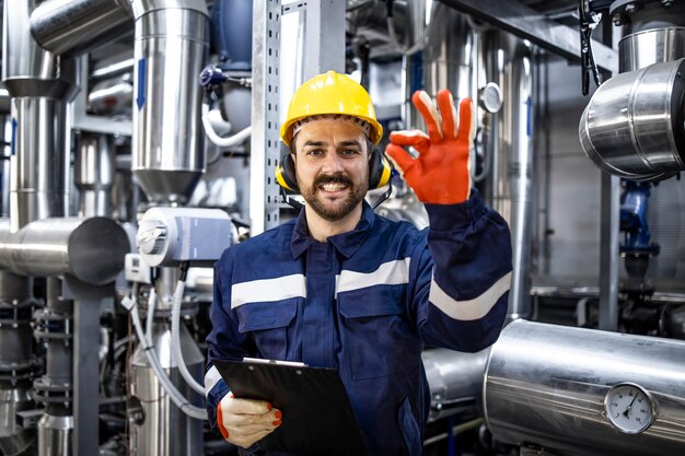 Foto produção de energia bem-sucedida e trabalhador de refinaria segurando sinal de ok