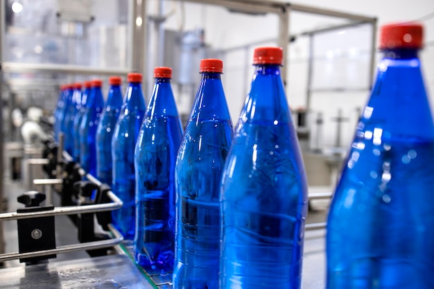 Foto producción de agua potable embotellada con interior de fábrica en segundo plano.