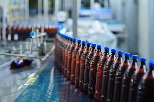 Producción alimentaria industrial de cerveza. Botellas de cerveza de plástico en una cinta transportadora en el fondo de una cervecería