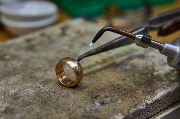 Foto producción de joyas. el joyero hace un anillo de oro.