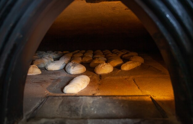 Producción de pan horneado con horno de leña en una panadería.