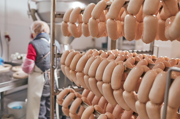 producción de salchichas de ternera, pollo y carne de cerdo, el trabajador sostiene salchichas en sus manos y