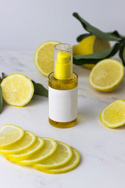 Producto cosmético de color amarillo en el fondo de limones sobre un fondo blanco.