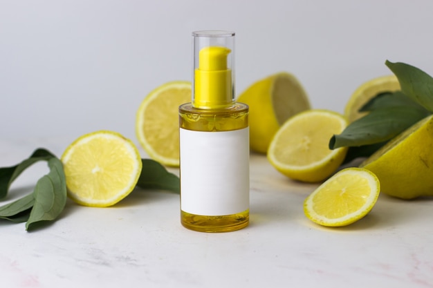 Producto cosmético de color amarillo en el fondo de limones sobre un fondo blanco.