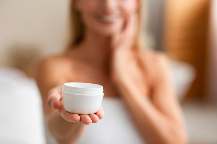 Foto producto para el cuidado de la piel mujer madura sosteniendo frasco con crema nutritiva enfoque selectivo
