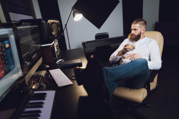 El productor masculino se sienta en el estudio de grabación.