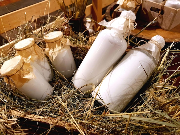 Productos agrícolas saludables latas de aluminio y botellas de vidrio con leche natural fresca en el heno en el pajar ...