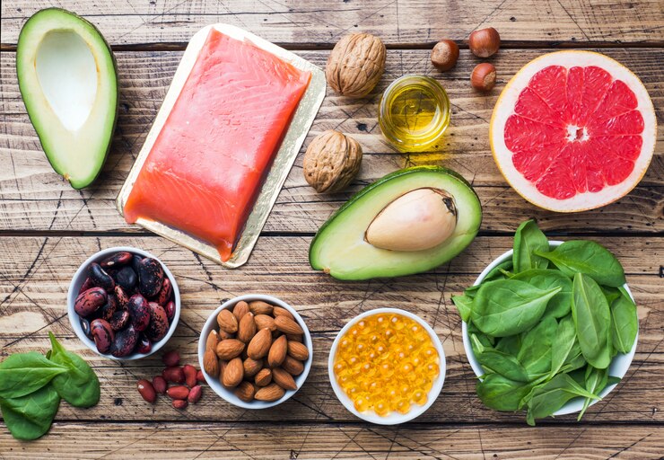 Productos antioxidantes de alimentos saludables: pescado y aguacate, nueces y aceite de pescado, pomelo sobre fondo de madera.