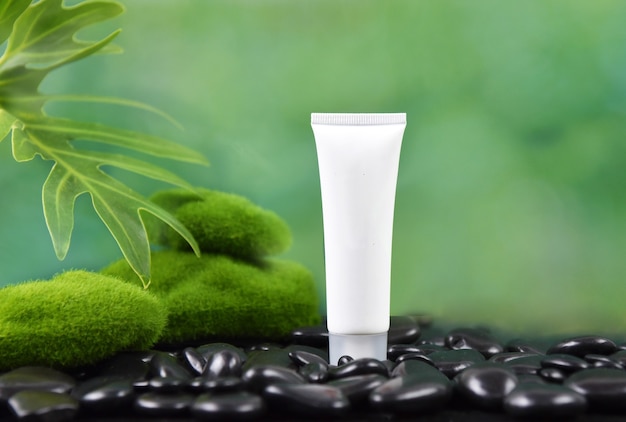 Productos de belleza con hojas verdes frescas y piedra negra.