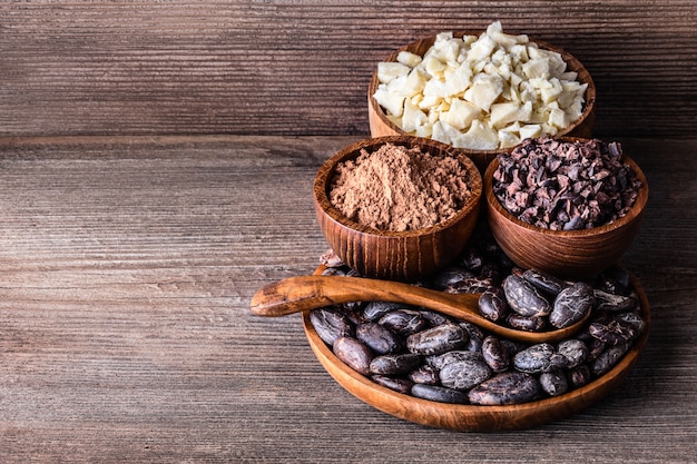 Los productos de cacao en cuencos de madera cuchara en la vieja mesa rústica.