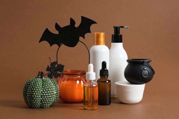 Productos cosméticos y decoración de halloween sobre fondo marrón.