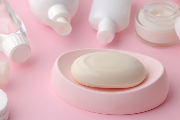 Productos para el cuidado del cuerpo y la piel en envases blancos sobre un delicado fondo rosa. Productos de higiene personal.