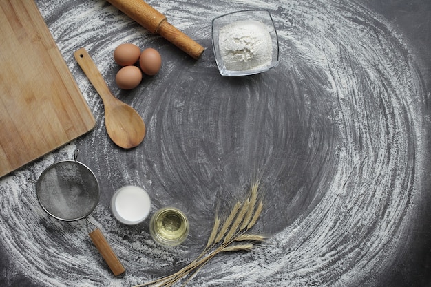 Productos y herramientas para hornear pan o pasteles en una mesa gris en harina esparcida