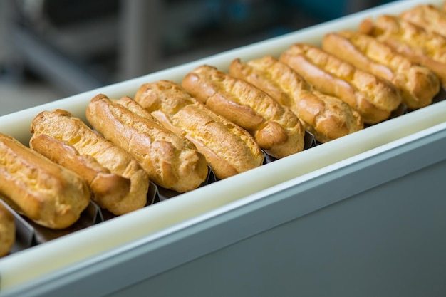 Productos horneados en cinta transportadora Cinta transportadora estrecha con conchas de eclair Estándar único de forma Fabricación de alimentos en la planta