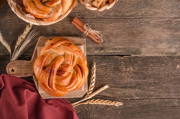 Productos horneados frescos - delicioso bollo de mimbre y canela con espacio de copia sobre fondo de madera