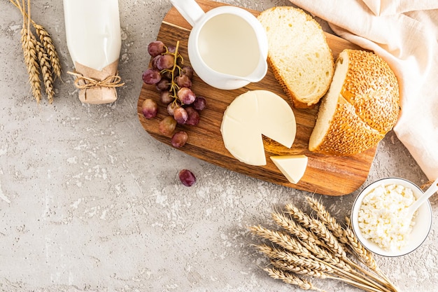 Productos lácteos frescos una hogaza de pan un ramo de mazorcas de maíz manzanas para la celebración del shavuot judío vista superior un espacio de copia