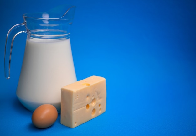 Productos lácteos. Leche, huevo y queso en una pared azul