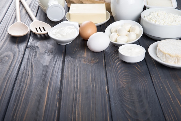 Productos lácteos en mesa de madera. Leche, queso, huevo, requesón y mantequilla.
