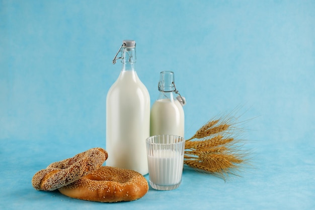 Foto productos lácteos pan botellas de leche sobre fondo azul claro festividad judía shavuot concepto