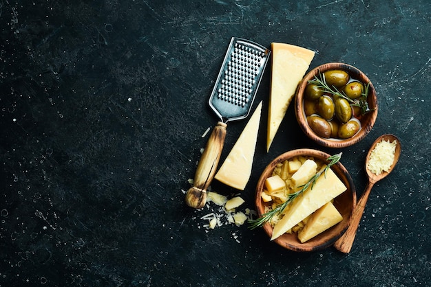 Productos lácteos Queso parmesano Aceitunas y bocadillos en una mesa de piedra Vista superior Sobre un fondo de hormigón