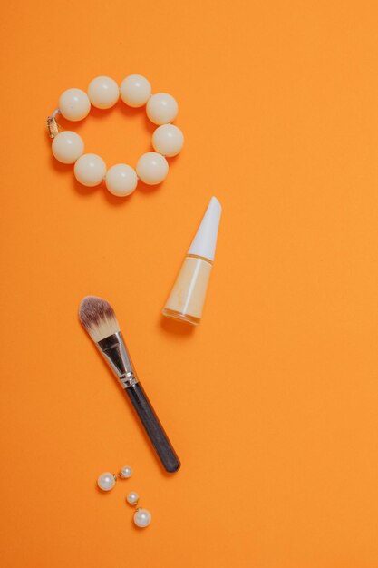 Productos de maquillaje, cosméticos y scrunchie sobre fondo naranja pastel. Vista plana endecha, superior. Plantilla de banner de blog de belleza.