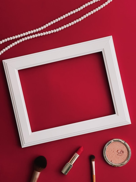 Productos de maquillaje de marco de arte horizontal blanco y joyas de perlas sobre fondo rojo como impresión de arte de diseño plano o concepto de álbum de fotos